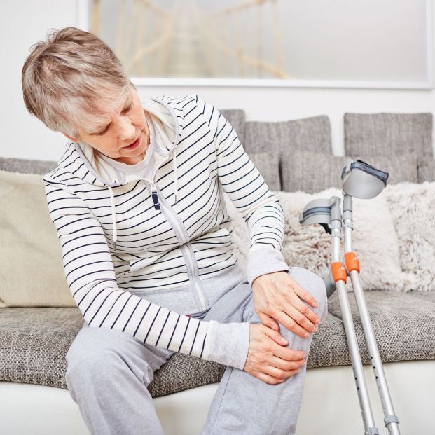 Mujer con dolor en la rodilla junto a sus muletas