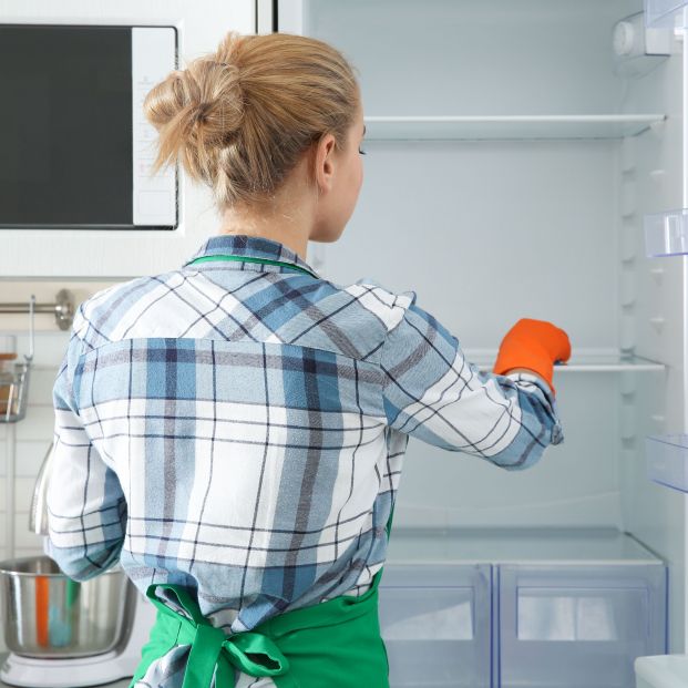 Mujer limpiando nevera para conservar los alimentos (bigstock)