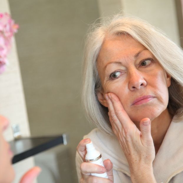 Mujer madura aplicándose crema para lucir una piel más joven  (bigstock)